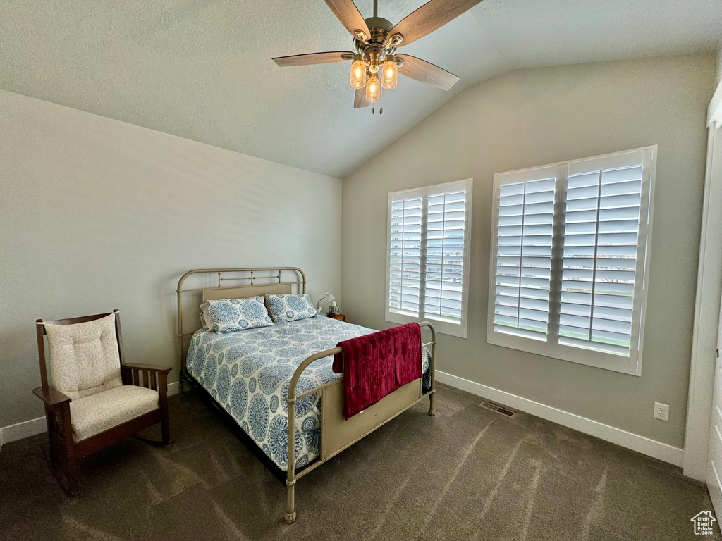 Bedroom with lofted ceiling, dark colored carpet, and ceiling fan