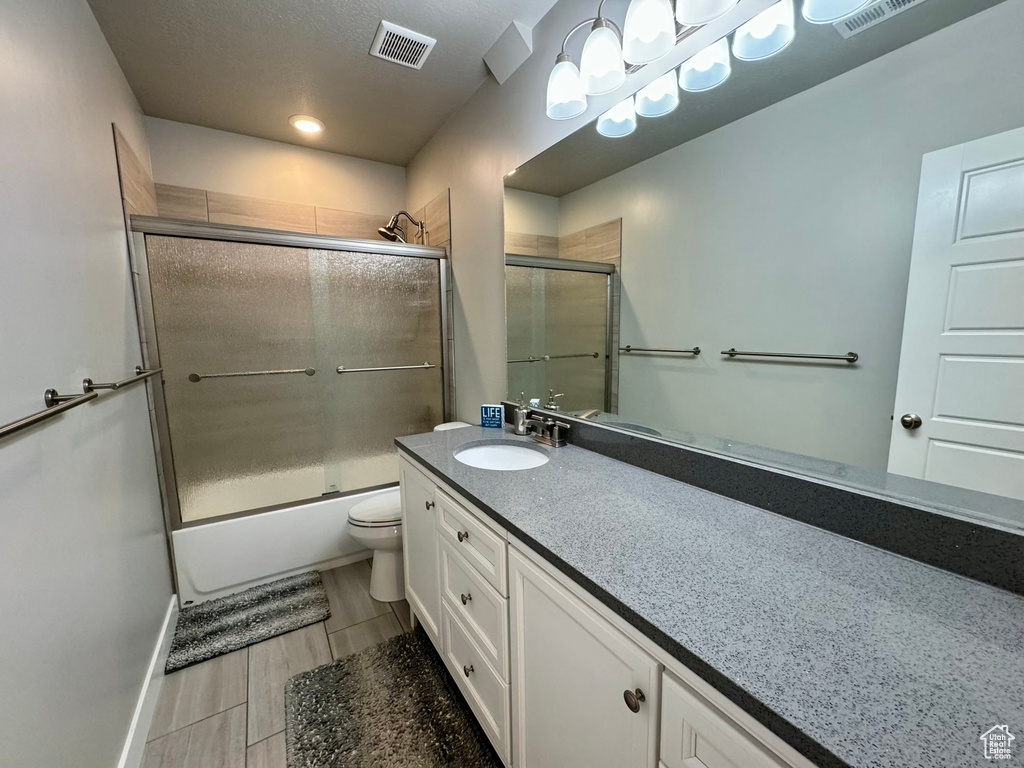 Full bathroom with toilet, enclosed tub / shower combo, tile flooring, a textured ceiling, and large vanity