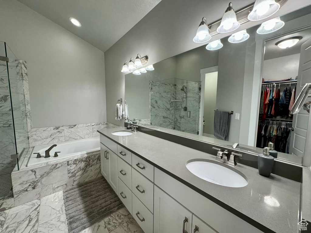 Bathroom featuring shower with separate bathtub, tile floors, double sink, and vanity with extensive cabinet space