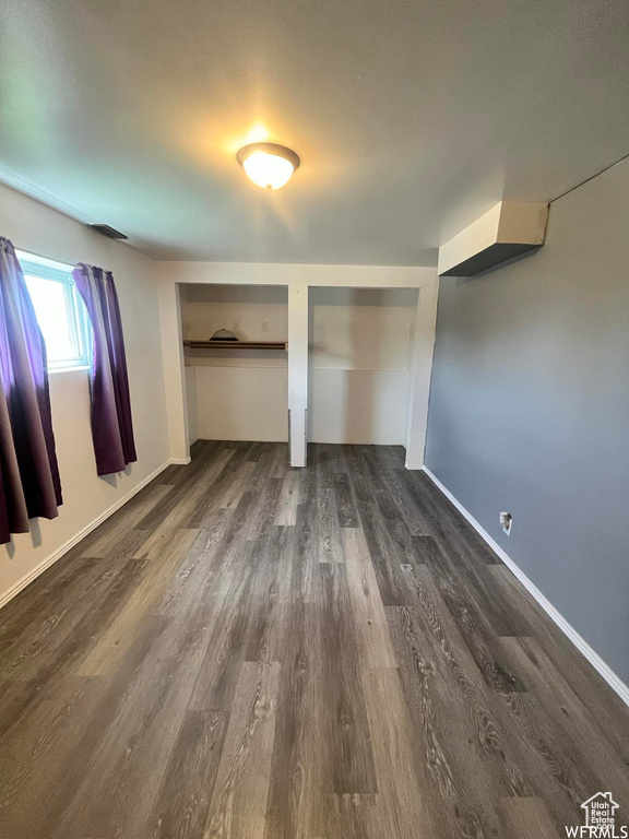 Unfurnished bedroom with dark hardwood / wood-style flooring and two closets