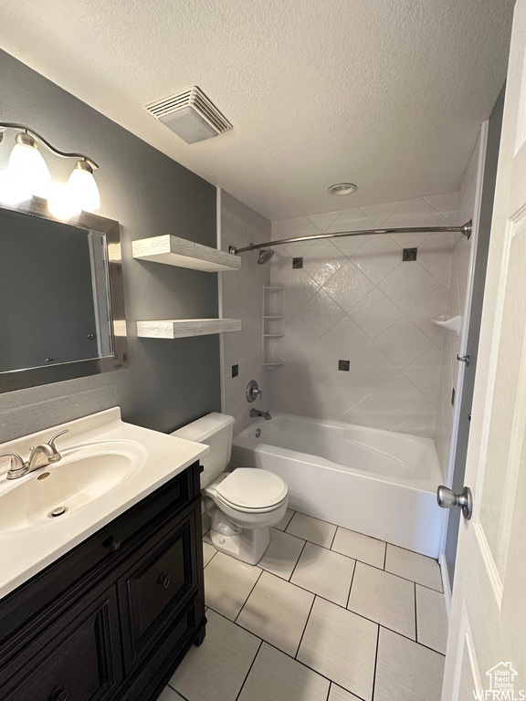 Full bathroom featuring toilet, tiled shower / bath combo, a textured ceiling, vanity, and tile floors