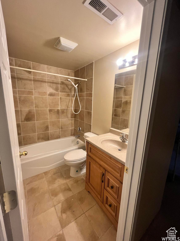 Full bathroom with tile floors, tiled shower / bath, toilet, and large vanity