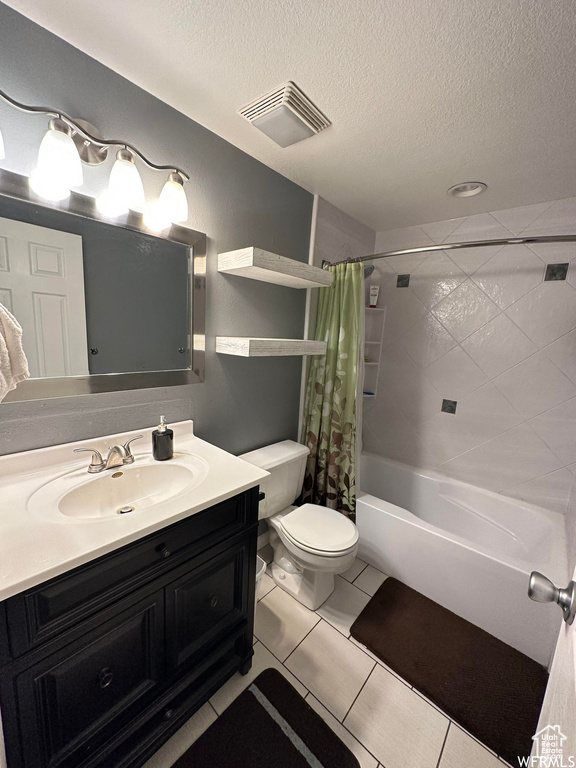 Full bathroom with toilet, vanity with extensive cabinet space, shower / bath combination with curtain, tile flooring, and a textured ceiling
