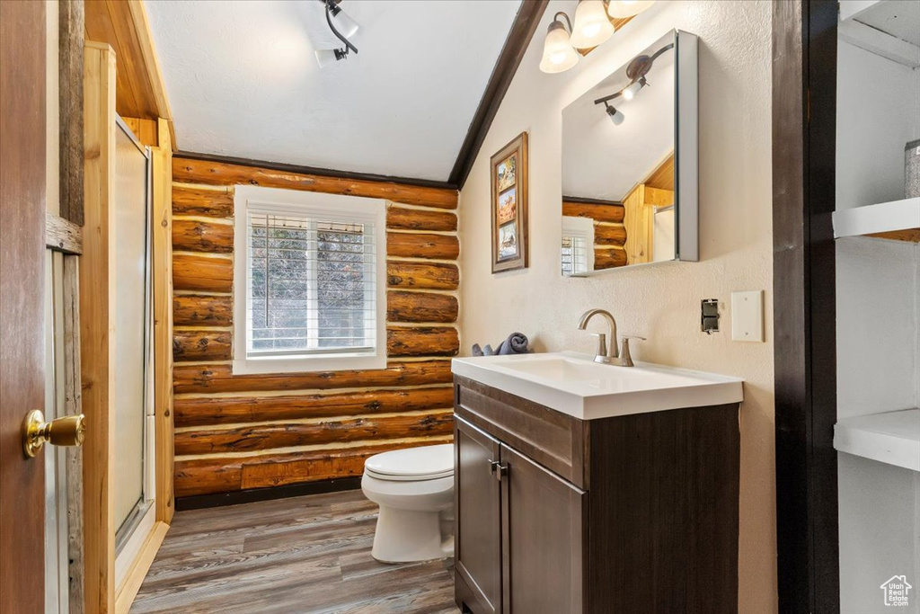 Bathroom with lofted ceiling, oversized vanity, rustic walls, and rail lighting