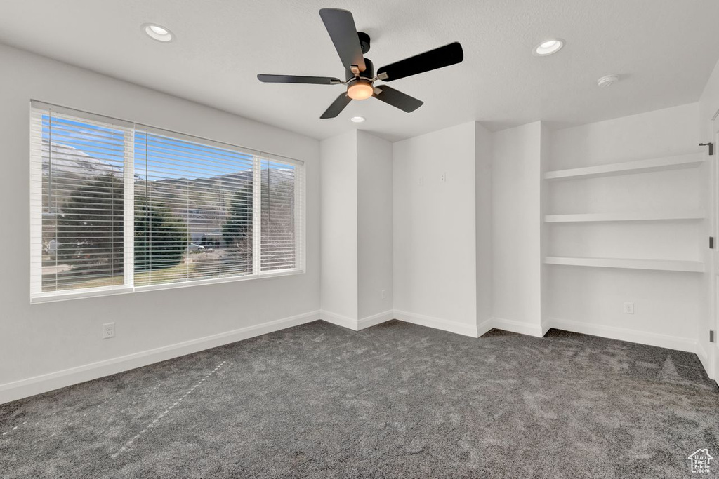 Carpeted spare room featuring plenty of natural light and ceiling fan