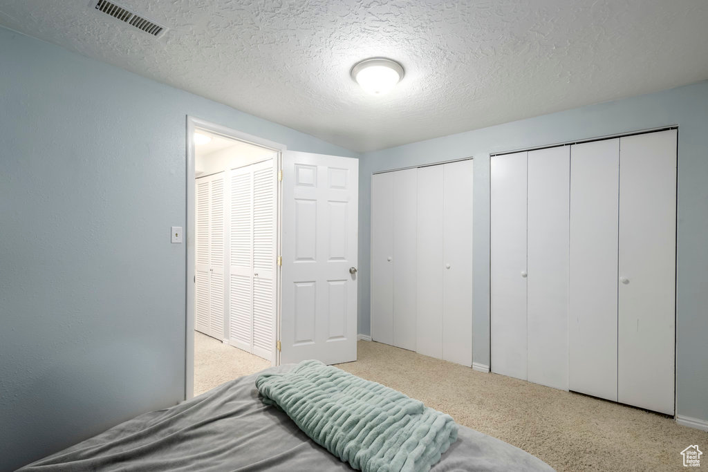Carpeted bedroom featuring a textured ceiling and two closets