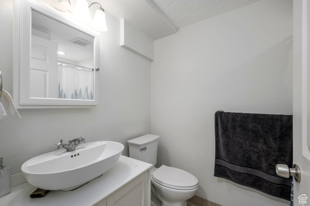 Bathroom featuring toilet, a textured ceiling, and vanity