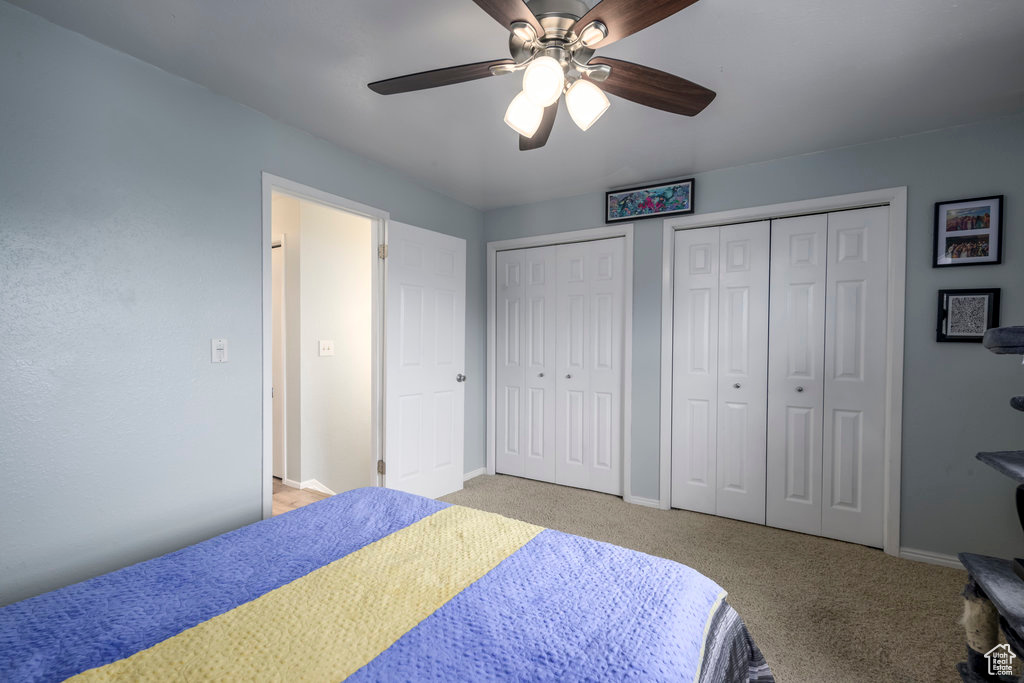 Carpeted bedroom featuring two closets and ceiling fan