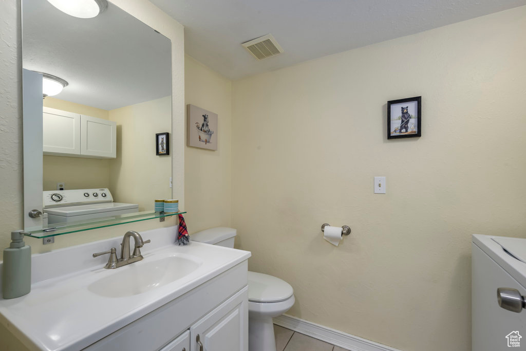 Bathroom featuring tile floors, toilet, vanity, and washer / dryer