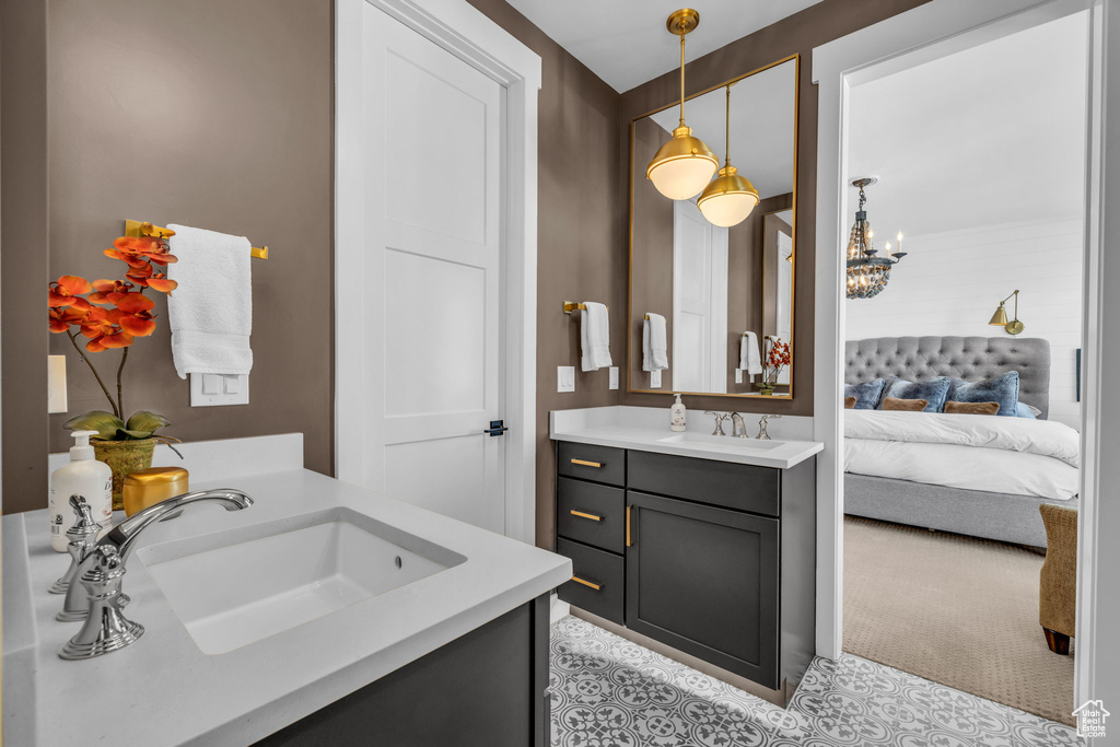 Bathroom featuring vanity with extensive cabinet space, tile flooring, and an inviting chandelier
