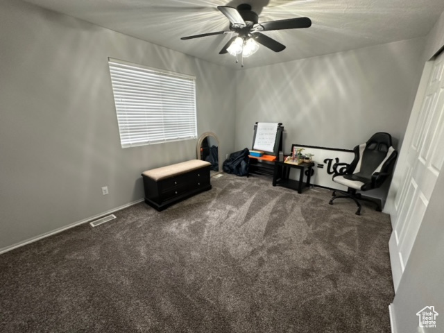 Sitting room featuring dark colored carpet and ceiling fan