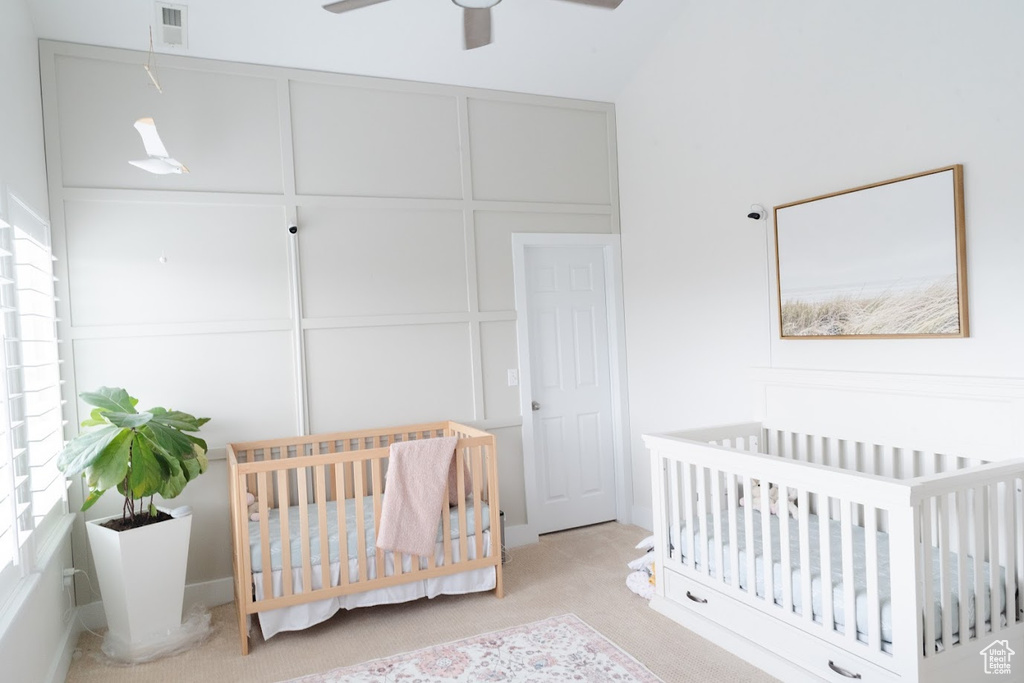 Bedroom with light carpet, a crib, and ceiling fan