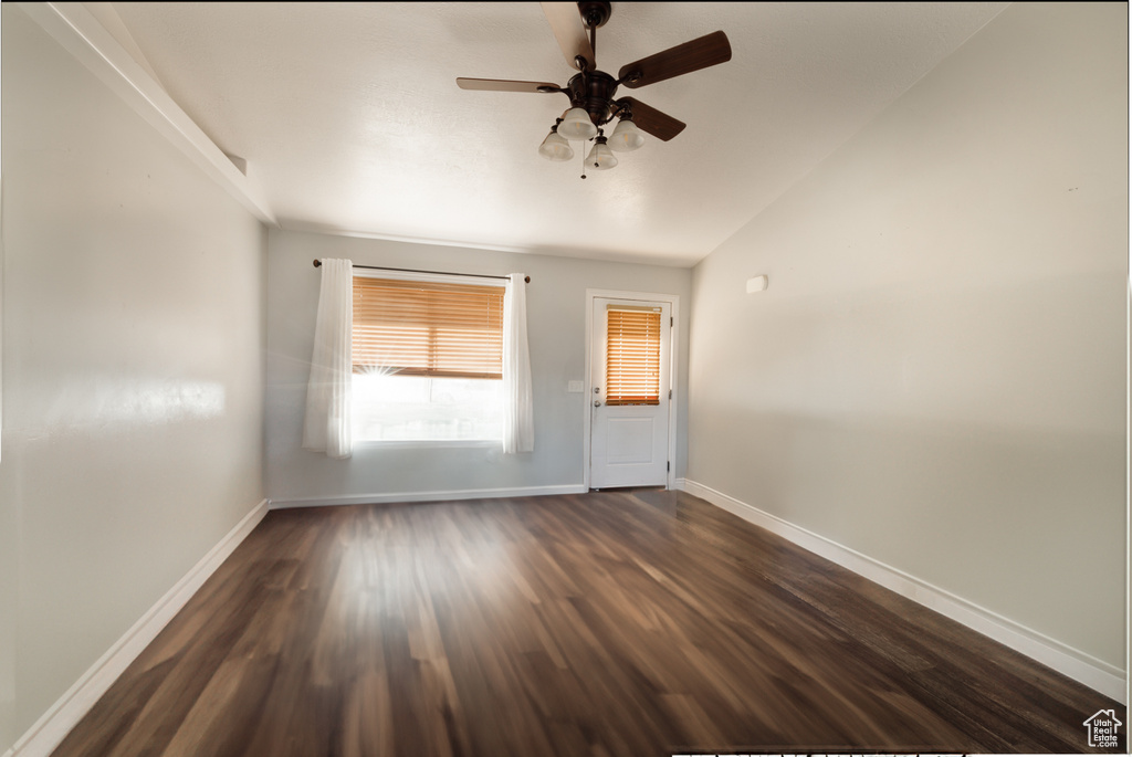 Unfurnished room featuring vaulted ceiling, ceiling fan, and dark hardwood / wood-style floors