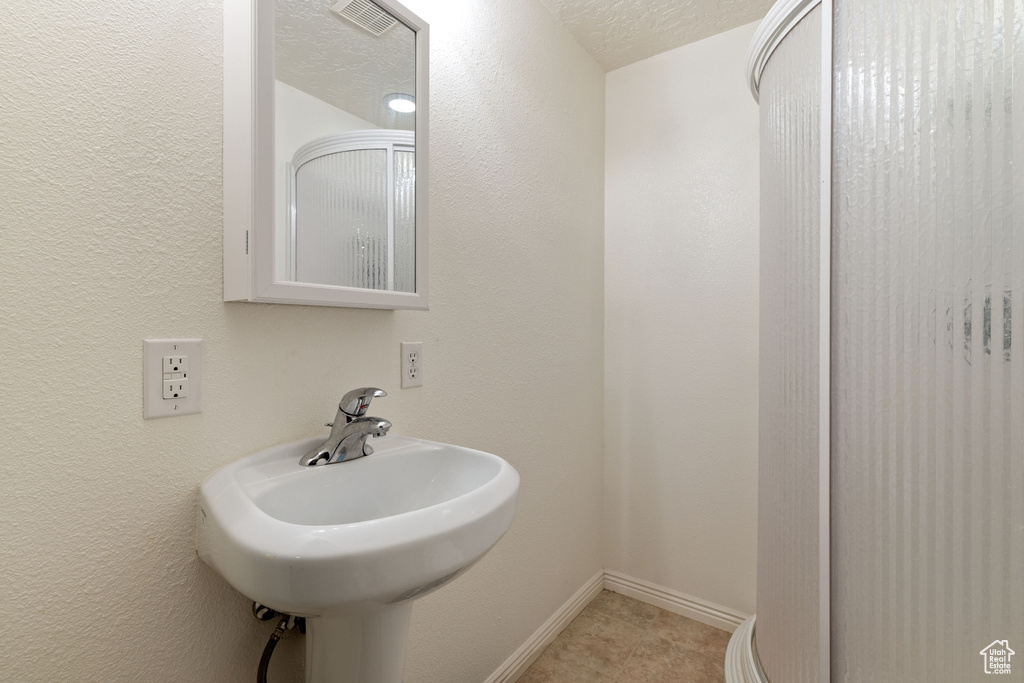 Bathroom featuring a textured ceiling, tile floors, and sink
