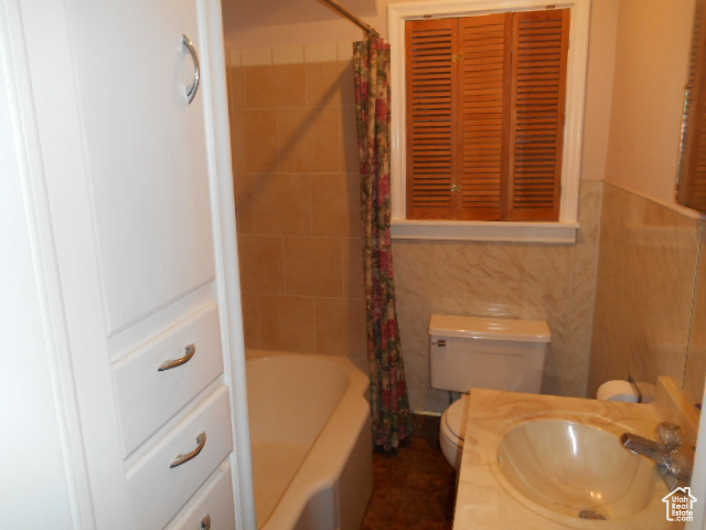 Full bathroom featuring shower / bath combination with curtain, toilet, and sink