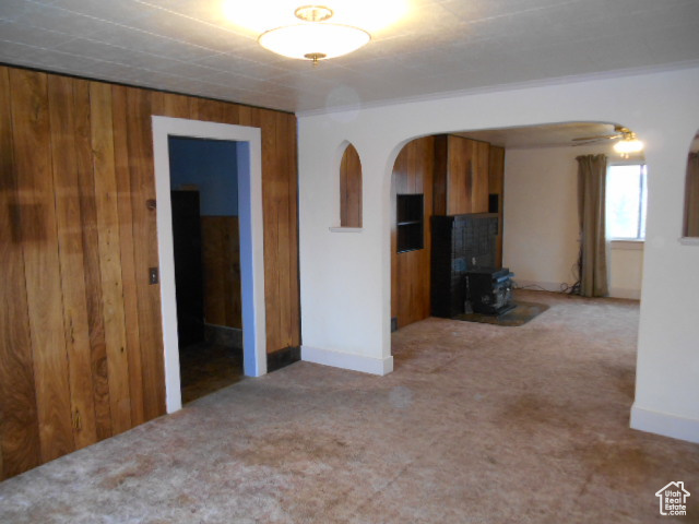 Interior space with wood walls, a wood stove, and ceiling fan