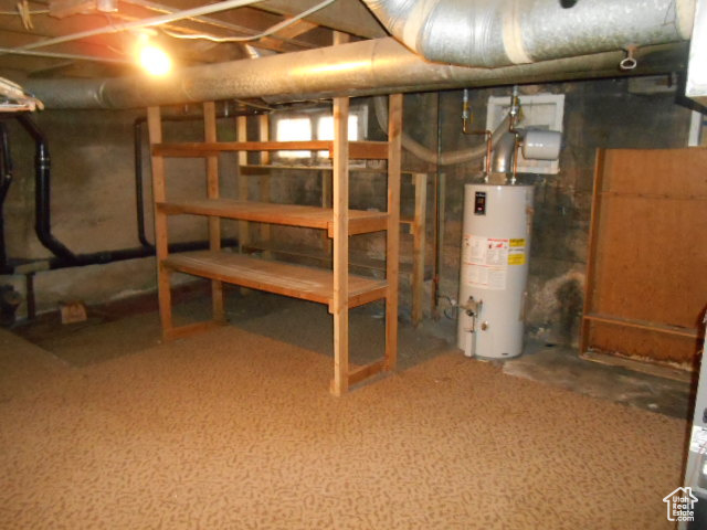 Basement featuring water heater and dark carpet