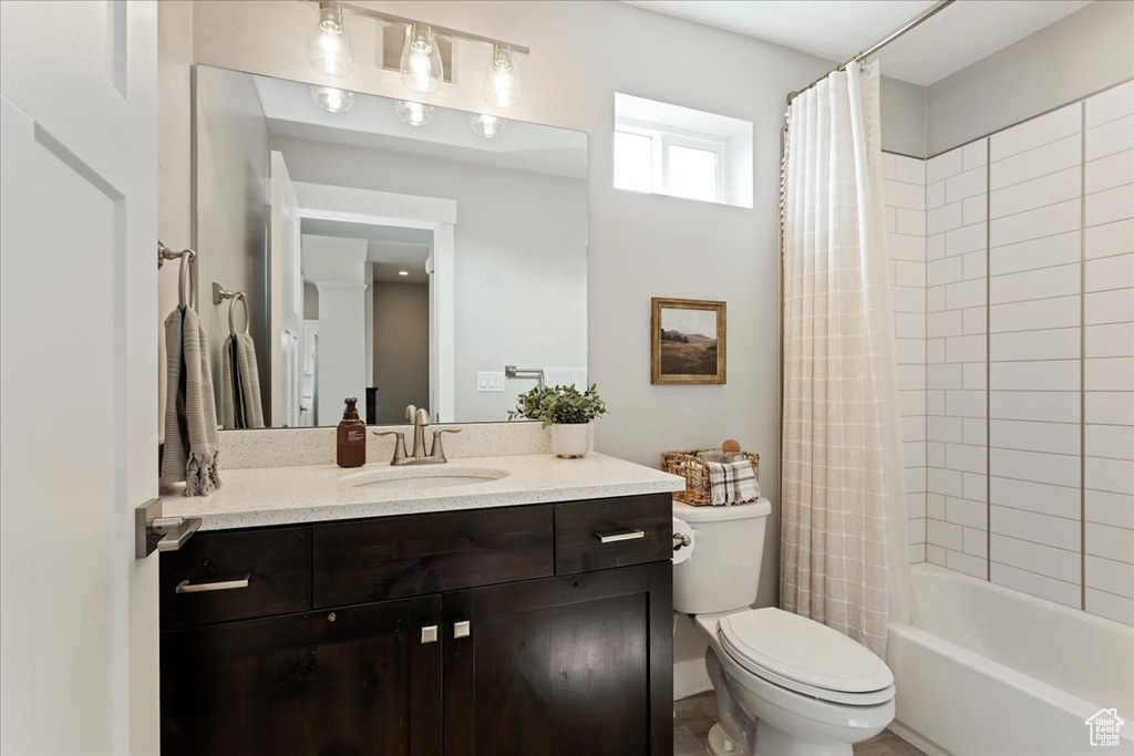 Full bathroom featuring toilet, shower / bathtub combination with curtain, and oversized vanity