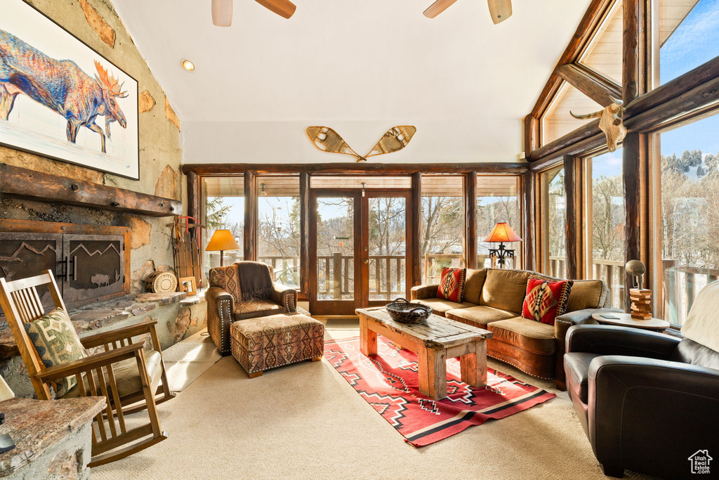 Living room with high vaulted ceiling, ceiling fan, and a stone fireplace