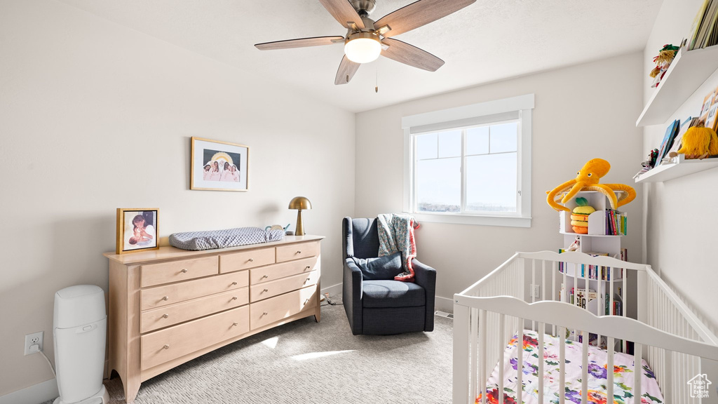 Bedroom with a nursery area, light colored carpet, and ceiling fan