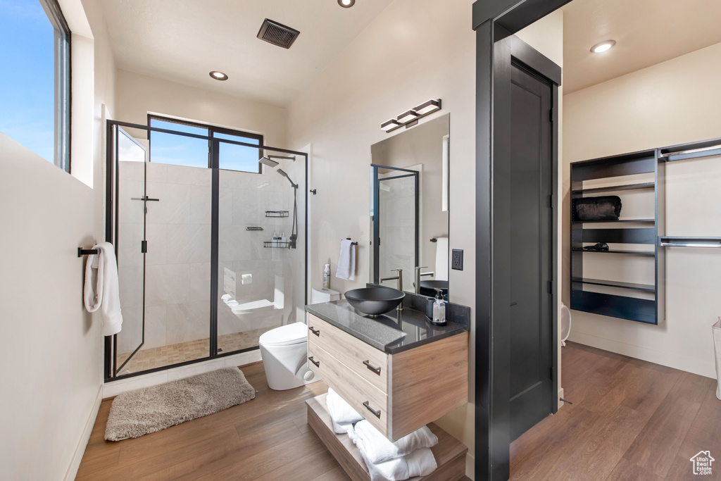 Bathroom featuring an enclosed shower, hardwood / wood-style floors, toilet, and dual bowl vanity