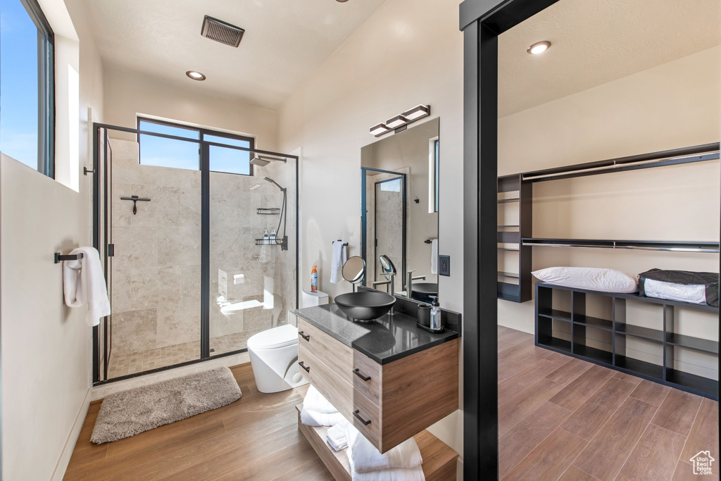 Bathroom with hardwood / wood-style flooring, walk in shower, double vanity, and toilet