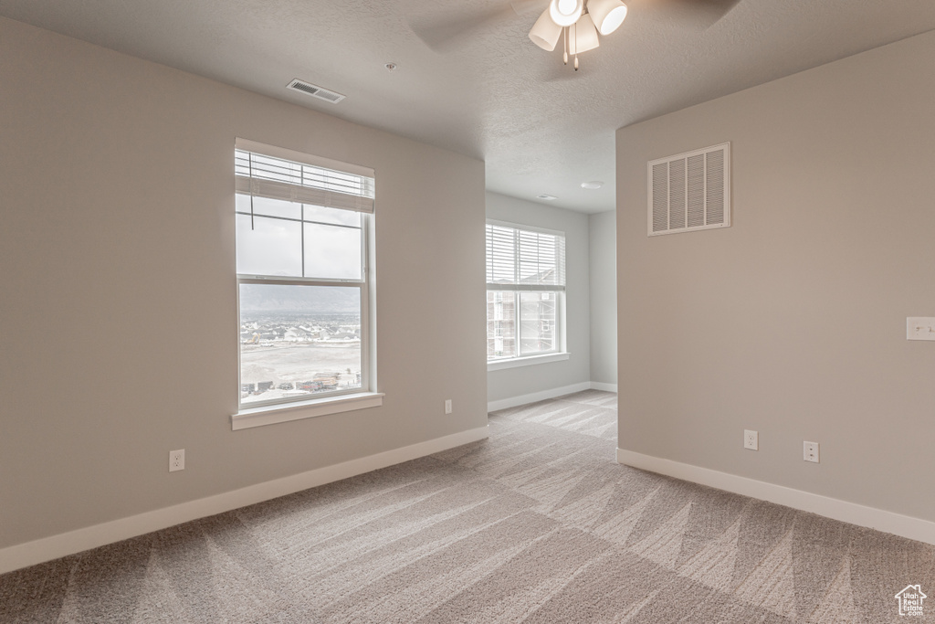 Carpeted spare room featuring ceiling fan and a textured ceiling