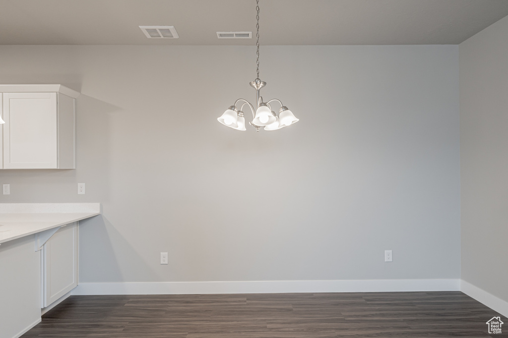 Unfurnished dining area with dark hardwood / wood-style flooring and a chandelier