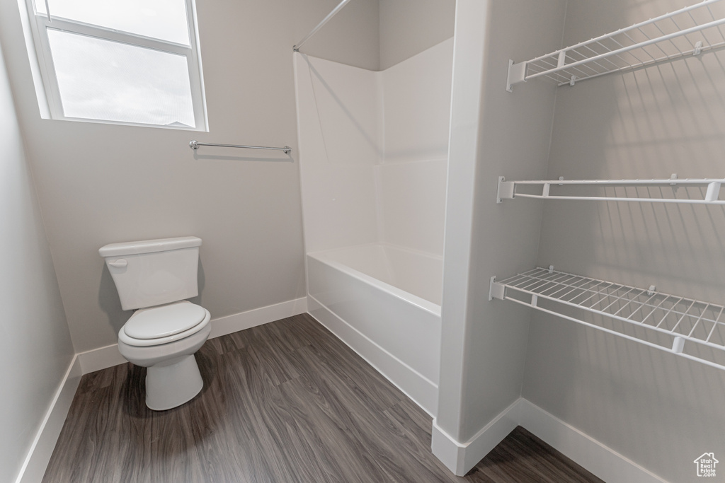 Bathroom with hardwood / wood-style floors, toilet, and  shower combination