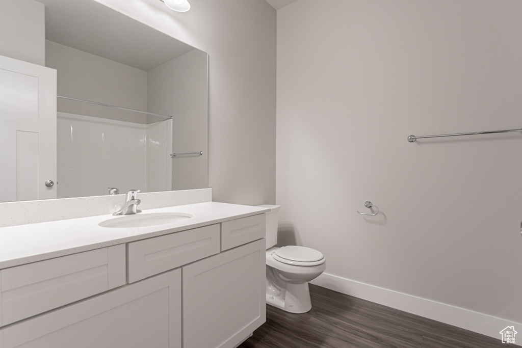 Bathroom featuring a shower, hardwood / wood-style flooring, vanity, and toilet