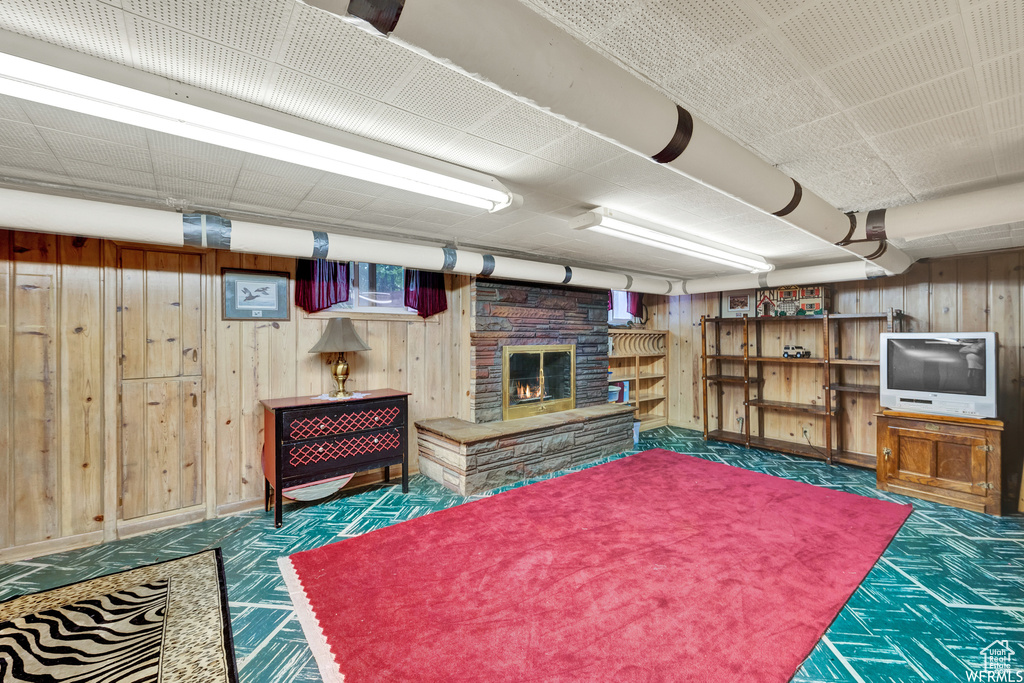 Basement featuring wooden walls, a fireplace, and dark colored carpet