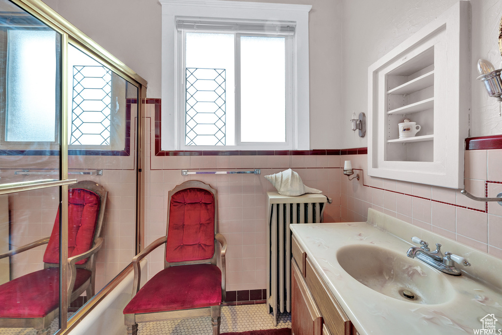 Bathroom with tile floors, a wealth of natural light, radiator, and large vanity