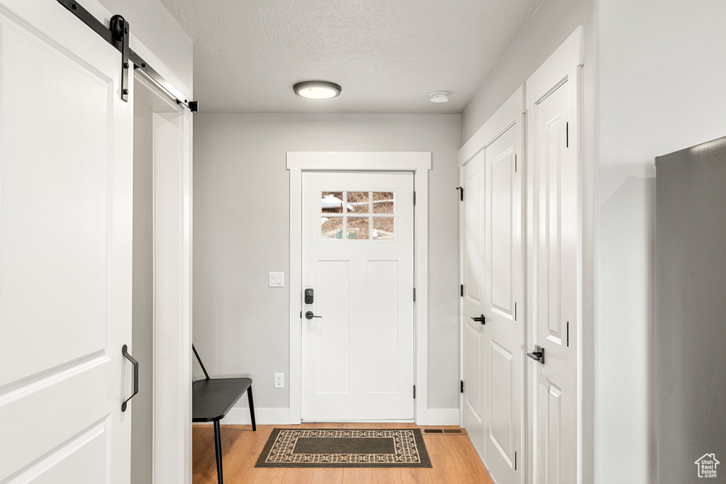 Entryway featuring a barn door, a textured ceiling, and light wood-type flooring