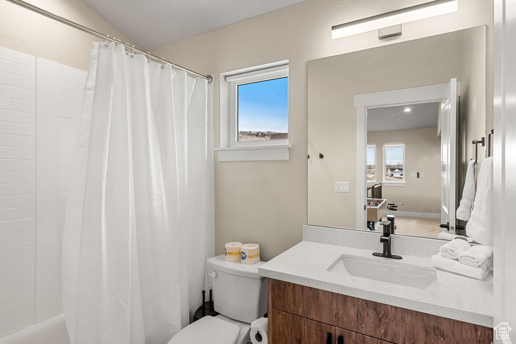 Bathroom with toilet, large vanity, and a wealth of natural light