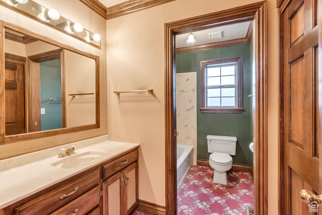 Full bathroom featuring crown molding, toilet, large vanity, and tub / shower combination