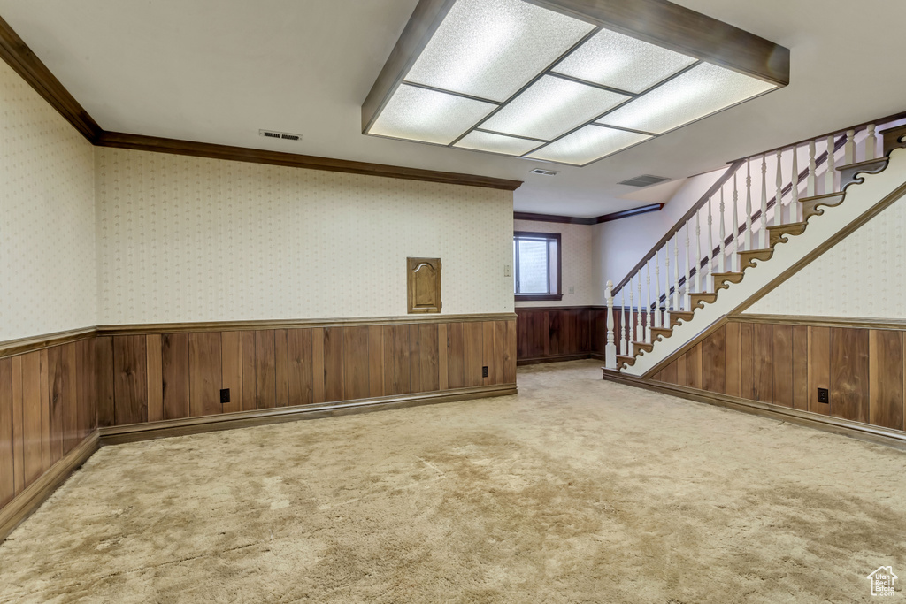 Interior space featuring crown molding, light colored carpet, and wood walls