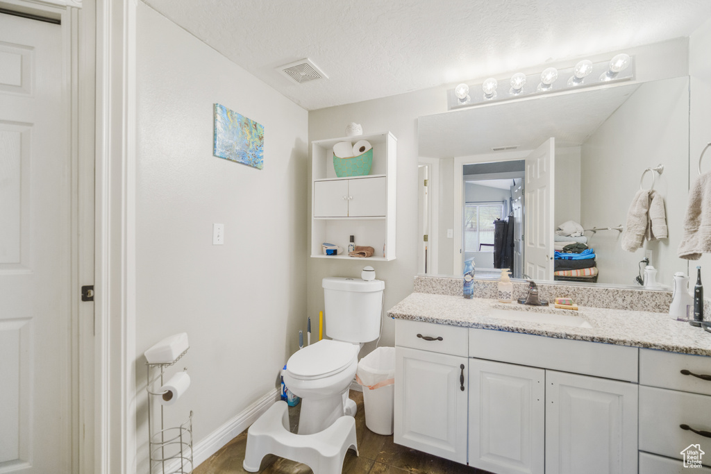 Bathroom with toilet, tile floors, a textured ceiling, and vanity