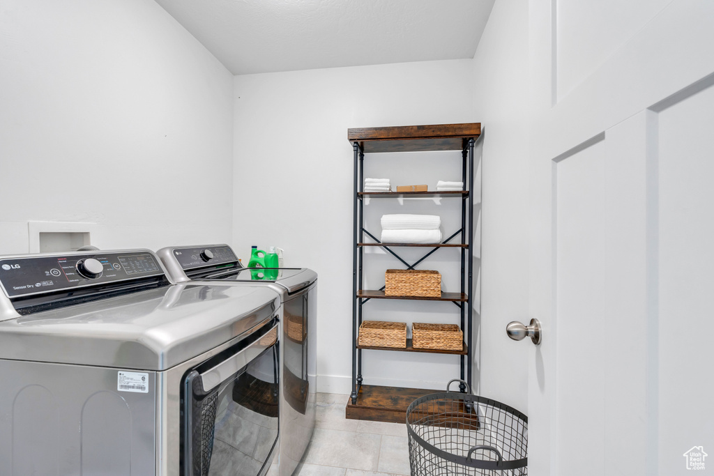 Clothes washing area with washer and dryer and light tile flooring