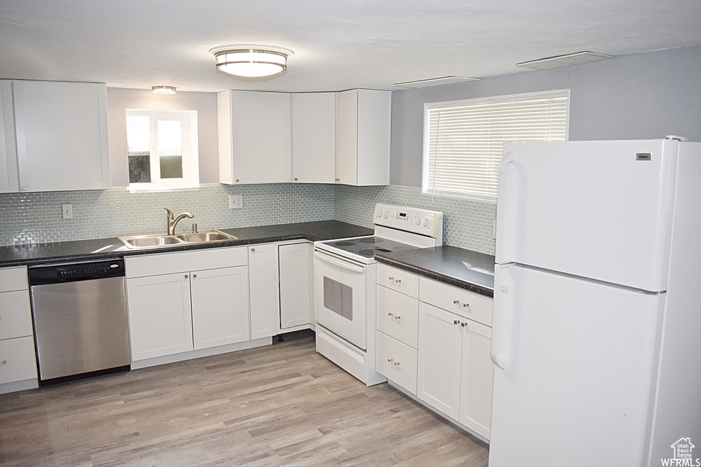 Kitchen with white appliances, sink, white cabinets, light hardwood / wood-style flooring, and backsplash