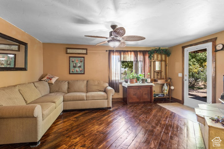 Living room featuring plenty of natural light, ceiling fan, and dark wood-type flooring