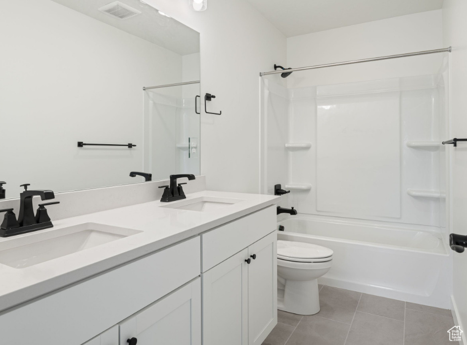 Full bathroom featuring shower / bath combination, dual vanity, tile floors, and toilet