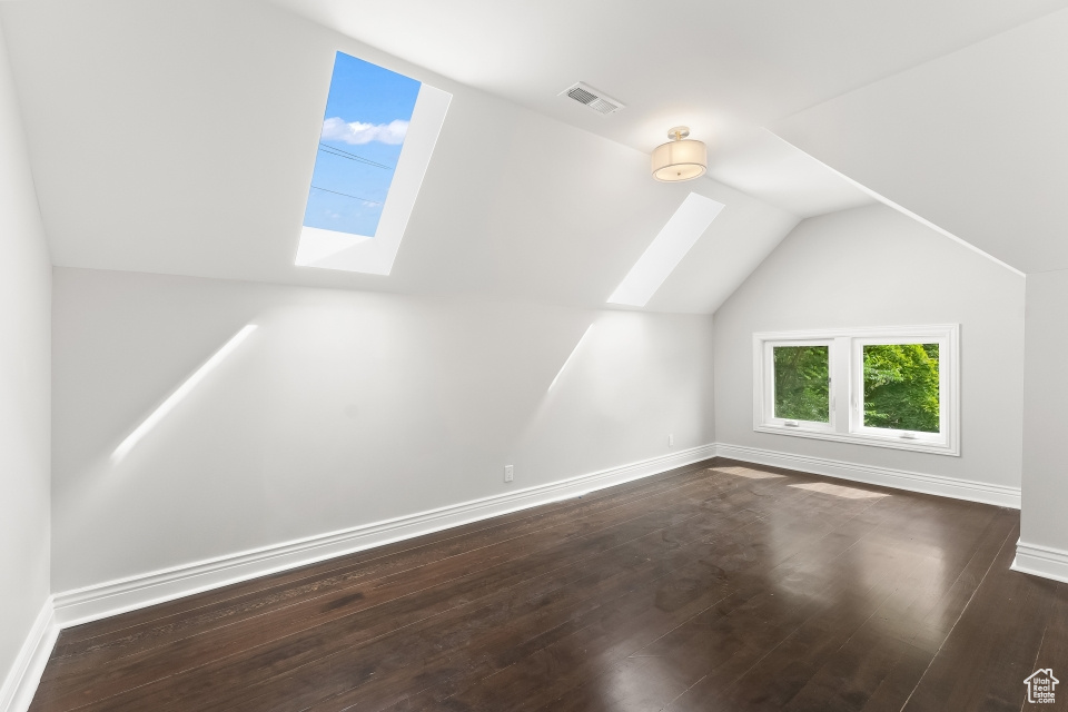 Bonus room featuring vaulted ceiling with skylight and dark hardwood / wood-style flooring