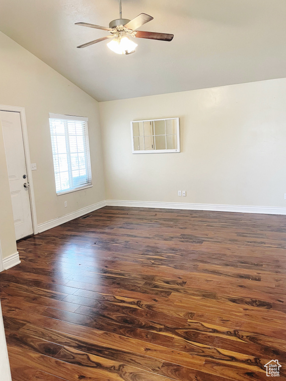 Empty room with dark wood-type flooring, ceiling fan, and lofted ceiling