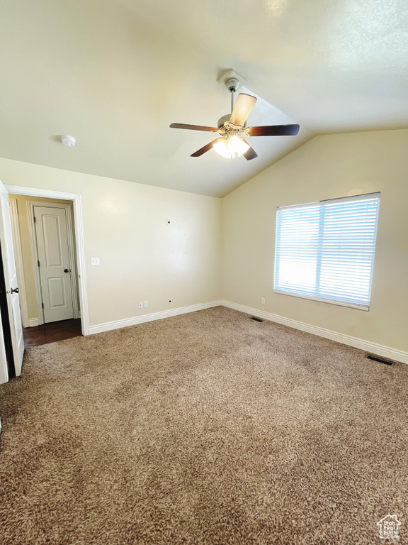 Spare room featuring ceiling fan, vaulted ceiling, and carpet flooring