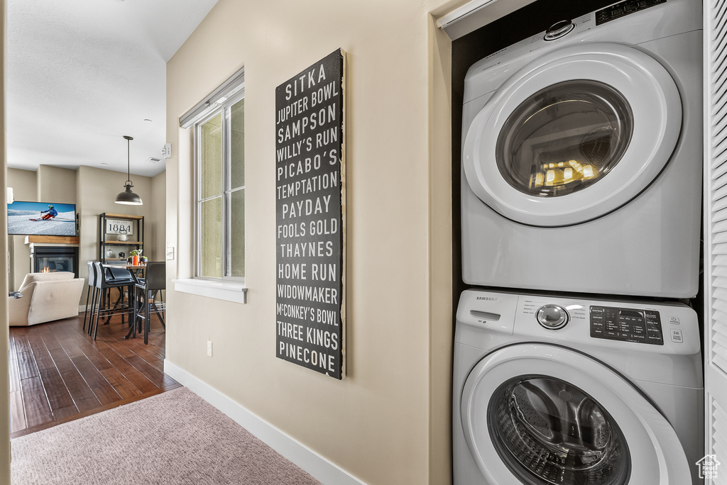 Laundry area featuring dark hardwood / wood-style floors and stacked washer / drying machine