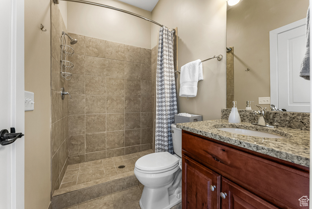 Bathroom featuring curtained shower, tile floors, large vanity, and toilet