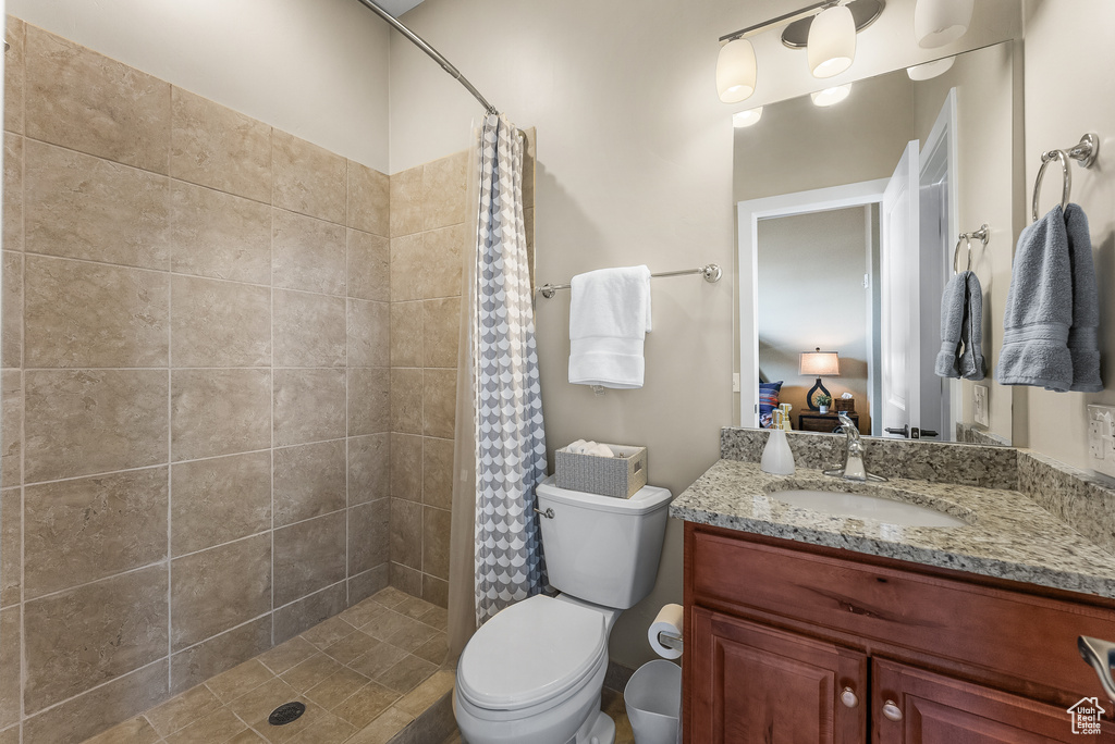 Bathroom with a shower with shower curtain, vanity with extensive cabinet space, and toilet