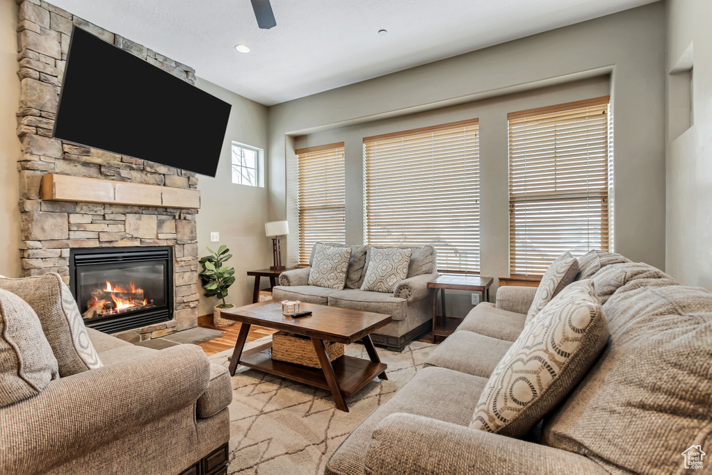 Living room featuring a stone fireplace and ceiling fan