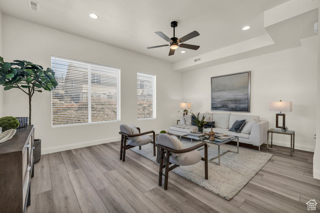 Living room featuring a tray ceiling, light hardwood / wood-style floors, and ceiling fan