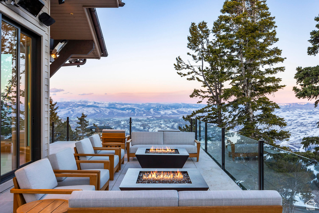 Patio terrace at dusk with a mountain view and an outdoor living space with a fire pit